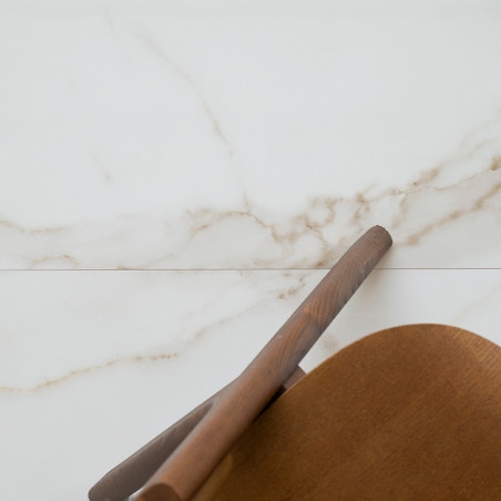 Chaise en bois partiellement visible, adossée à un mur en marbre blanc poli aux subtiles veines beiges, dans un décor minimalist