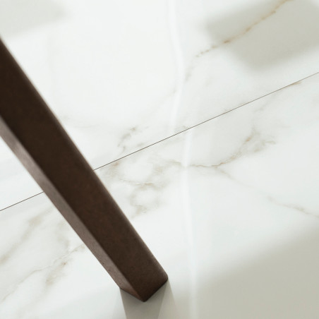 Un carrelage marbré blanc et lisse se trouve sous un pied de table en bois, projetant une légère ombre, suggérant un décor intér