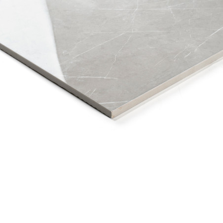 A smooth, rectangular, grey tile with subtle white veining rests on a white surface, reflecting light for a glossy appearance.