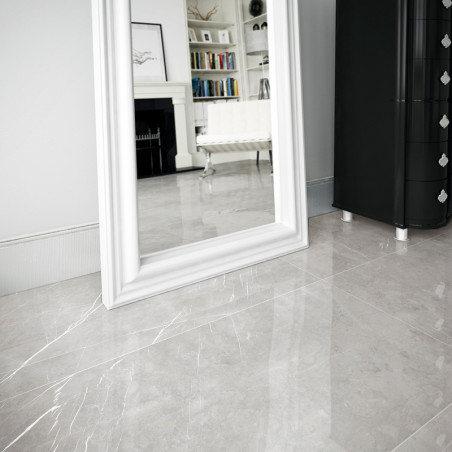 A large, reflective white-tiled floor enhances the spaciousness of a room, featuring a white-framed mirror and black dresser, wi