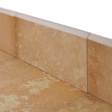 Los rodapies de cerámica beige se encuentran en la base de una pared, ligeramente texturizados, rodeados por líneas de lechada y rodapies adyacentes, lo que indica una configuración de piso.