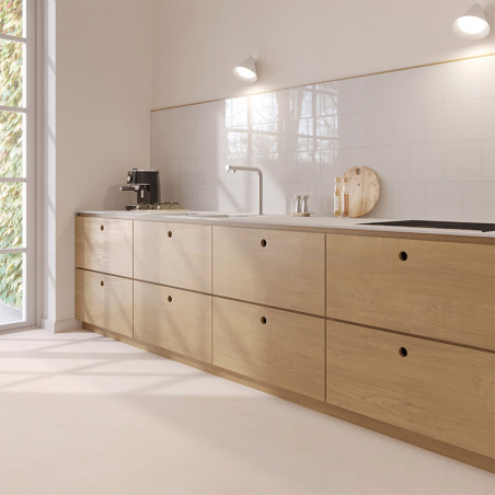 Een moderne keuken is voorzien van lichte houten kasten tegen wit betegelde muren. Op het aanrecht staan ​​een koffiezetapparaat