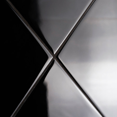 Four glossy, black ceramic tiles meet at a central point, forming an `X` with light reflections accentuating their smooth surfac