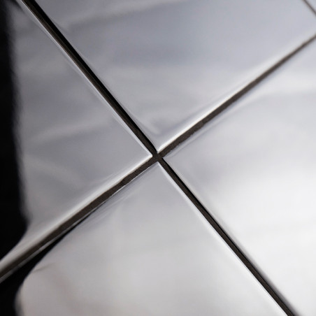 Vier glänzende, metallische Kacheln sind in einem Raster angeordnet und reflektieren Licht und Schatten. Sie bilden sich kreuzen