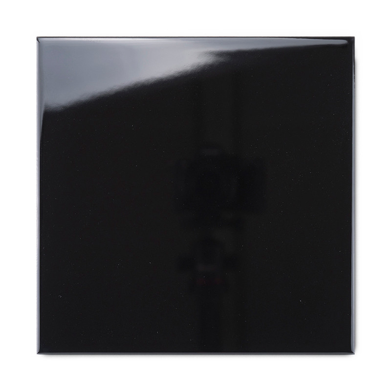Eine glänzende schwarze Fliese reflektiert Licht und erzeugt eine glänzende Oberfläche und eine schattige Reflexion vor einem mi