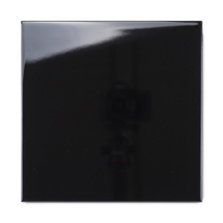 Eine glänzende schwarze Fliese reflektiert Licht und erzeugt eine glänzende Oberfläche und eine schattige Reflexion vor einem mi