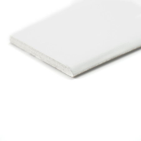 Um rodapé branco retangular fica plano e exibe uma superfície superior lisa e uma borda levemente texturizada em um fundo branco liso.