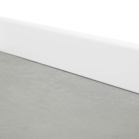 Um rodapé cinza liso fica plano, delimitado por um rodapé branco, na intersecção entre o chão e a parede em uma sala minimalista.