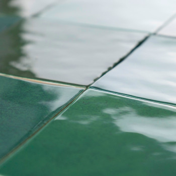 Groene keramische tegels vormen een rasterpatroon, reflecteren licht met een glanzende afwerking, waardoor een glad, levendig op