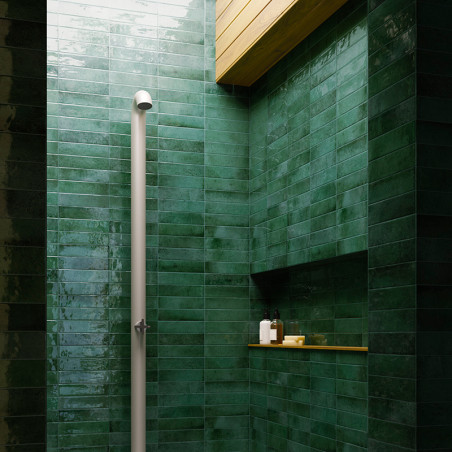 Een verticale witte douchekop is in een douche tegen glanzende donkergroene tegels geplaatst. Houten plafondpanelen zorgen voor 