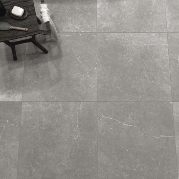 Graue Steinfliesen bedecken den Boden mit dezenten weißen Maserungen. An der Seite steht ein Holztisch mit Pflegeprodukten, der 