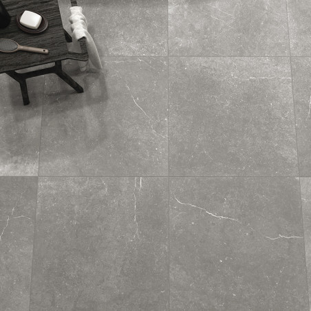 Graue Steinfliesen bedecken den Boden mit dezenten weißen Maserungen. An der Seite steht ein Holztisch mit Pflegeprodukten, der 