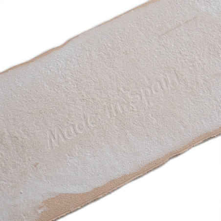 Auf einer rechteckigen Kachel ist der geprägte Text „Made in Spain“ zu sehen. Die Fliese hat eine strukturierte, beige Oberfläch