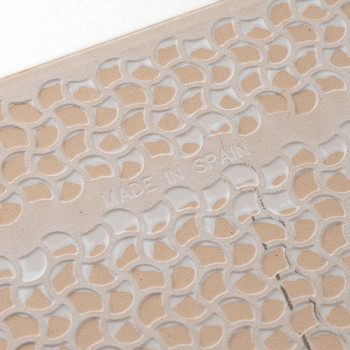 Un azulejo muestra un patrón de hojas tallado y repetitivo con `MADE IN SPAIN` en relieve, mostrando intrincados detalles de dis