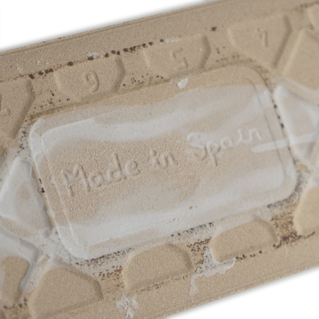 Op een beige tegel staat in een rechthoekig gebied de tekst `Made in Spain` in reliëf. De omringende cijfers `9` en `7` verschij