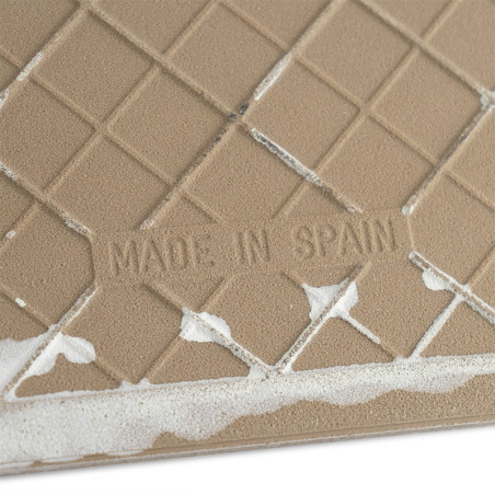 Eine hellbraune, strukturierte Keramikfliese trägt den Text „MADE IN SPAIN“ inmitten eines Gittermusters und ist an den Rändern 