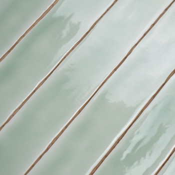 Carreaux rectangulaires, brillants, vert clair. alignés en diagonale. des lignes de coulis les séparent, créant un motif ordonné