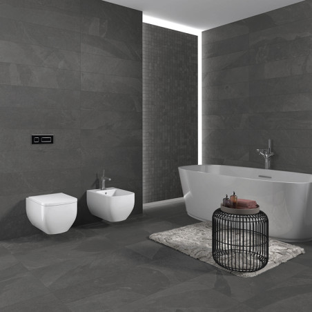 Un baño moderno cuenta con una gran bañera blanca junto a una pared de piedra oscura, con una mesa redonda de alambre sobre una 