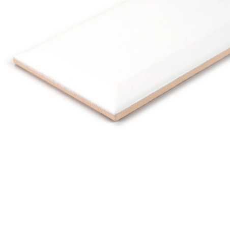 Un carreau de céramique rectangulaire blanc brillant repose sur une surface blanche unie, soulignant ses bords biseautés et sa t