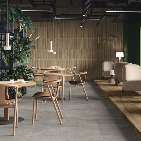 Des tables et des chaises en bois sont posées sur un sol carrelé gris clair dans un café moderne doté de verdure et d'un éclaira