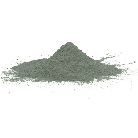 A greenish-gray powder forms a small mound, scattered on a white surface, suggesting preparation for mixing or use.