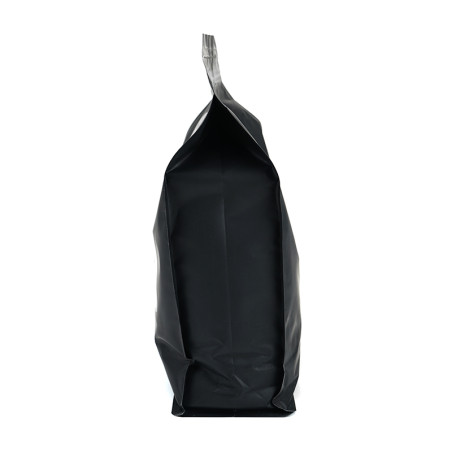 Una bolsa negra sellada se encuentra en posición vertical, sin marcar, sobre un fondo blanco liso, lo que sugiere un producto em