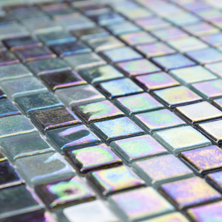 Iridescent glass tiles reflect light, creating a shimmering effect on a flat surface composed of small, square pieces.