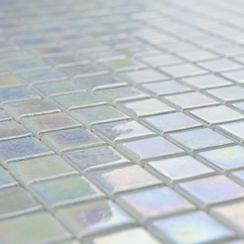 Iridescent glass tiles reflect light, creating a shimmering effect on a flat surface in a geometric grid pattern.