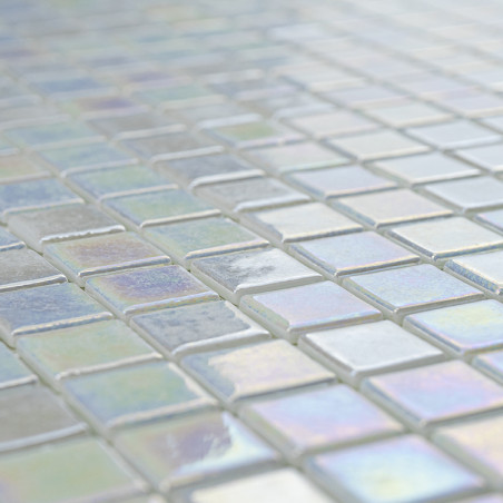 Iridescent glass tiles reflect light, creating a shimmering effect on a flat surface in a geometric grid pattern.