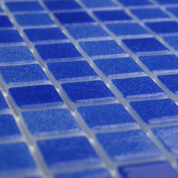Blue glass tiles form a grid, lying flat, creating a shimmering surface with light reflections.