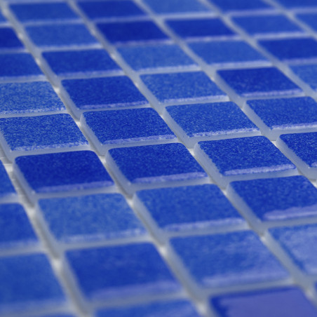 Blue glass tiles form a grid, lying flat, creating a shimmering surface with light reflections.