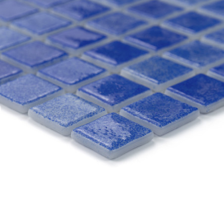 Blue glass tiles form a grid pattern, reflecting light subtly, placed on a smooth surface.