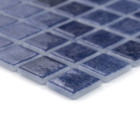 Azulejos de vidrio cuadradas azules colocadas muy cerca, formando un patrón de mosaico texturizado sobre una superficie plana.
