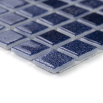 Blue glass tiles laid uniformly, reflecting light, form a sleek mosaic pattern on a flat surface.