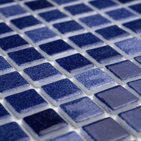Blue glass tiles arranged in a grid pattern, reflecting light, set on a white grout base.