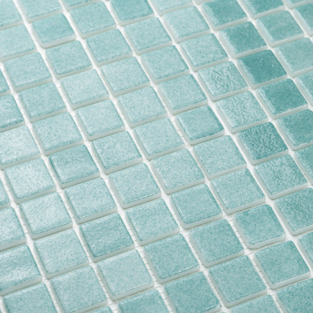 Turquoise glass tiles are neatly arranged in a grid pattern, creating a textured, reflective surface on a wall.