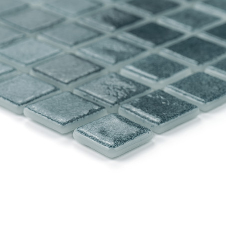 Square glass tiles arranged neatly, reflecting light subtly, in a grid pattern against a smooth white background.