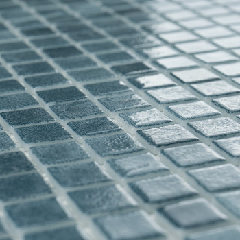 Blue glass tiles evenly arranged, reflecting light, create a shimmering effect in a grid-like pattern.