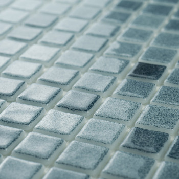 Glass mosaic tiles display varying blue shades, creating a shimmering effect in ambient light on a flat, uniform surface.