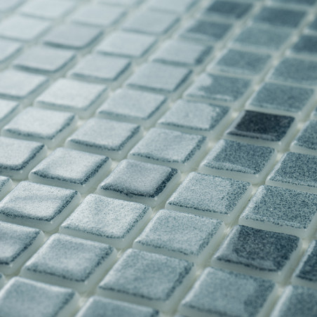 Glass mosaic tiles display varying blue shades, creating a shimmering effect in ambient light on a flat, uniform surface.