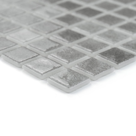 Square glass tiles rest in a grid pattern, reflecting light subtly in a minimalistic, modern setting.