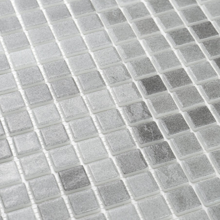 Glass tiles form a shiny, textured grid pattern, reflecting light subtly in a monochromatic, neutral-toned layout.