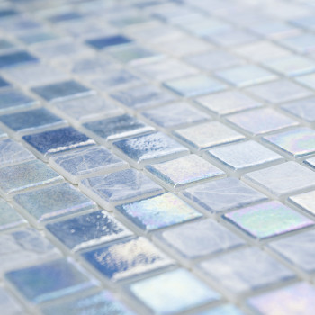 Iridescent glass mosaic tiles glisten on a surface, displaying varying shades of blue and white in a grid pattern.