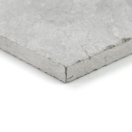 A textured, gray stone tile lies on a white surface, displaying its rough edges and smooth top.