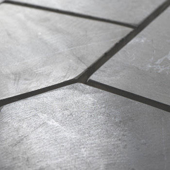 Stone tiles form an irregular, angled pattern on a smooth, slightly reflective surface, creating a textured visual effect.