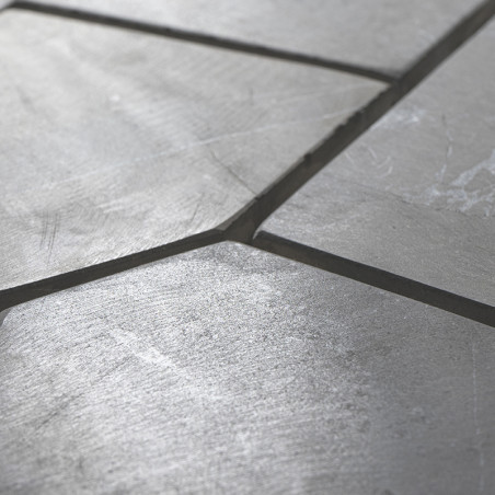 Stone tiles form an irregular, angled pattern on a smooth, slightly reflective surface, creating a textured visual effect.