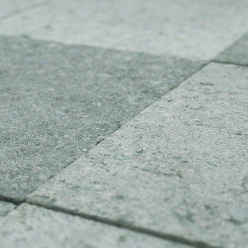 Gray stone tiles arranged in a grid lie evenly on the ground, forming a textured, uniform surface.