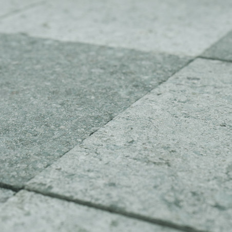 Gray stone tiles arranged in a grid lie evenly on the ground, forming a textured, uniform surface.