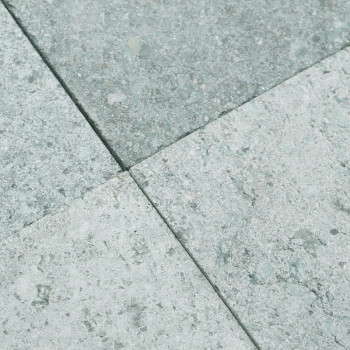 Stone tiles form a square pattern, featuring a textured surface of speckled light gray and pale green hues.