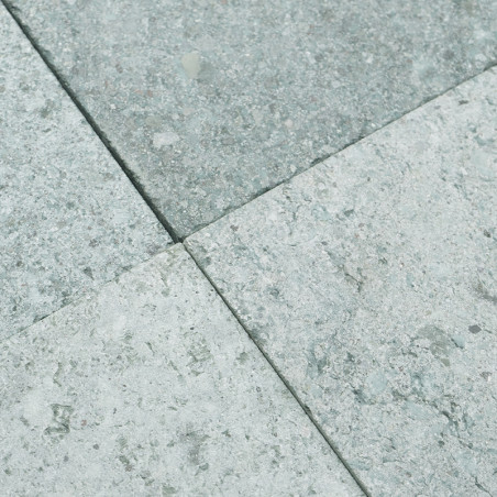 Stone tiles form a square pattern, featuring a textured surface of speckled light gray and pale green hues.
